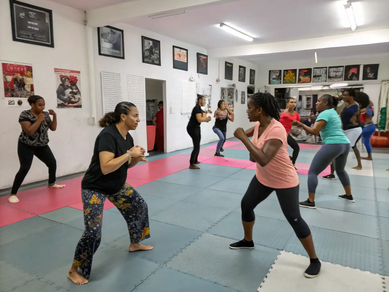 A woman demonstrating a self-defense technique during a workshop, with other participants practicing in the background.